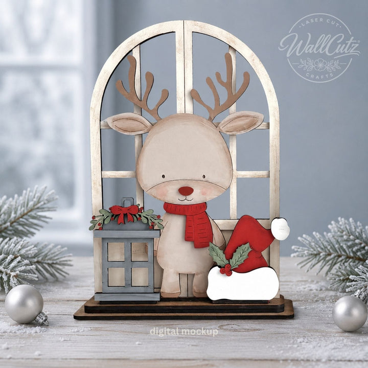 Christmas Reindeer wood window kit with painted reindeer, red scarf, lantern, and Santa hat in a snowy setting – WallCutz