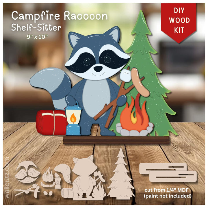 DIY wood kit for a campfire raccoon shelf-sitter, featuring a finished painted raccoon holding a lantern and roasting a sausage next to a green pine tree and campfire, with uncut MDF template pieces shown below on a wooden surface.